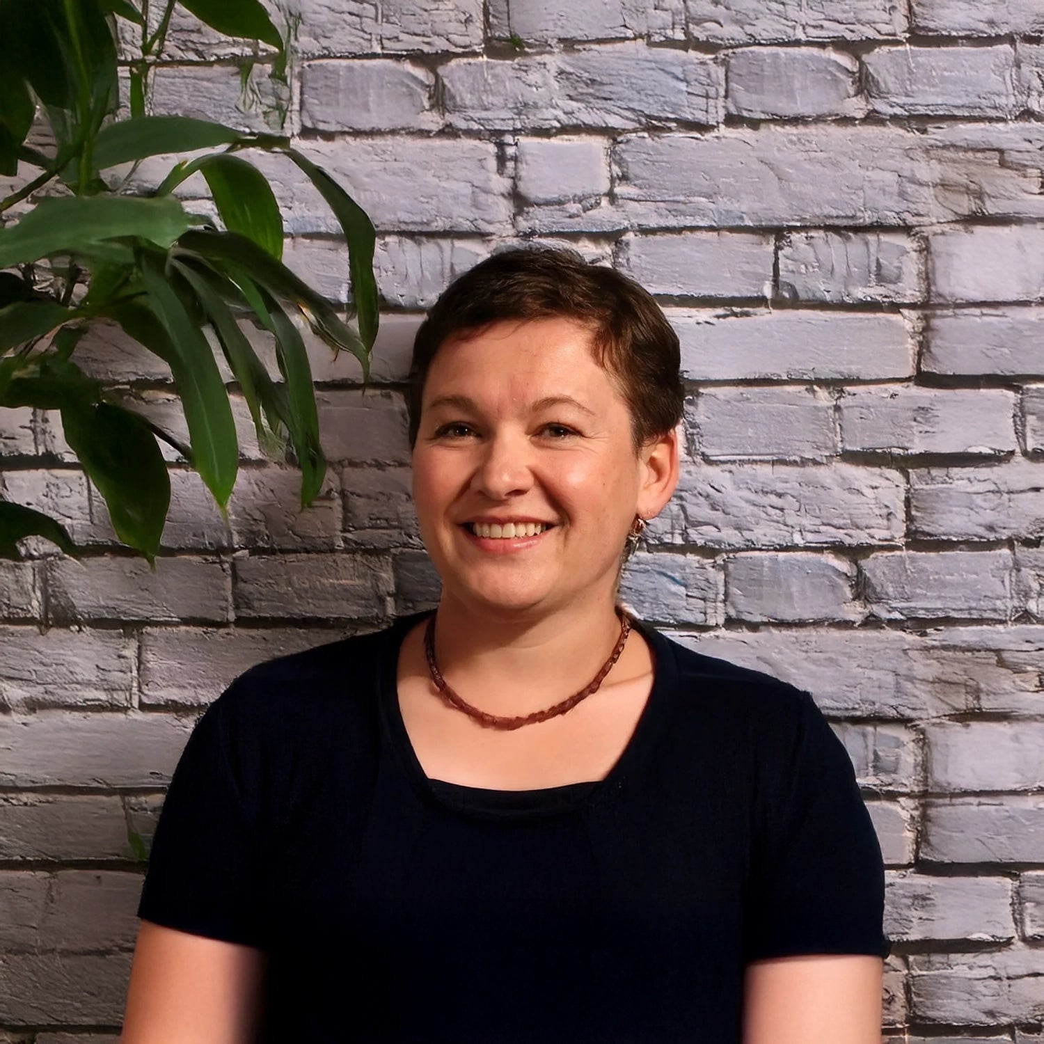 Hondenhoek voedingsexperte Jannie Pavlova glimlacht vriendelijk voor een witte bakstenen muur, met een grote groene kamerplant op de achtergrond. Als expert in hondenvoeding en welzijn deelt zij haar kennis over gezonde voeding, natuurlijke supplementen en evenwichtige voedingsschema’s voor honden van alle leeftijden. Haar deskundigheid speelt een centrale rol binnen het advies en de productkeuzes van Hondenhoek.com.